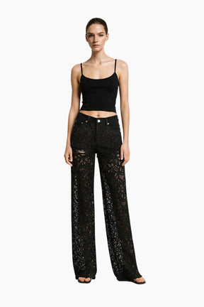 Model wearing black lace top and pants on a white background