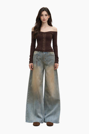 Woman wearing a brown off-shoulder top and wide-leg jeans on a white background
