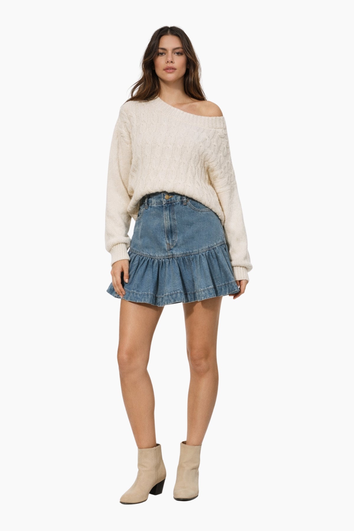 Woman wearing a cream sweater and denim skirt on a white background
