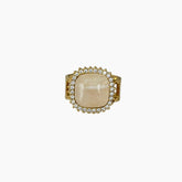 Gold ring with a large beige stone and smaller stones on a white background