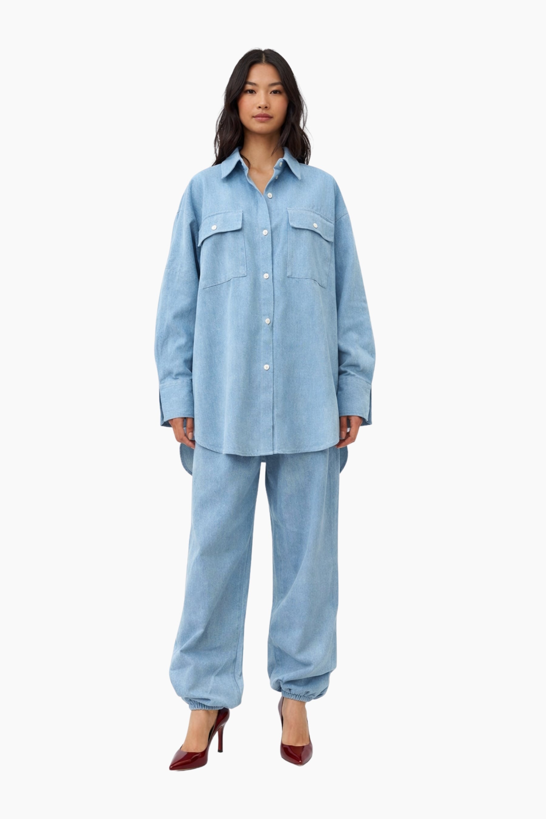 Woman wearing a light blue denim outfit on a white background