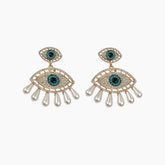 Pair of eye-shaped earrings with gemstones and pearl-like elements on a white background