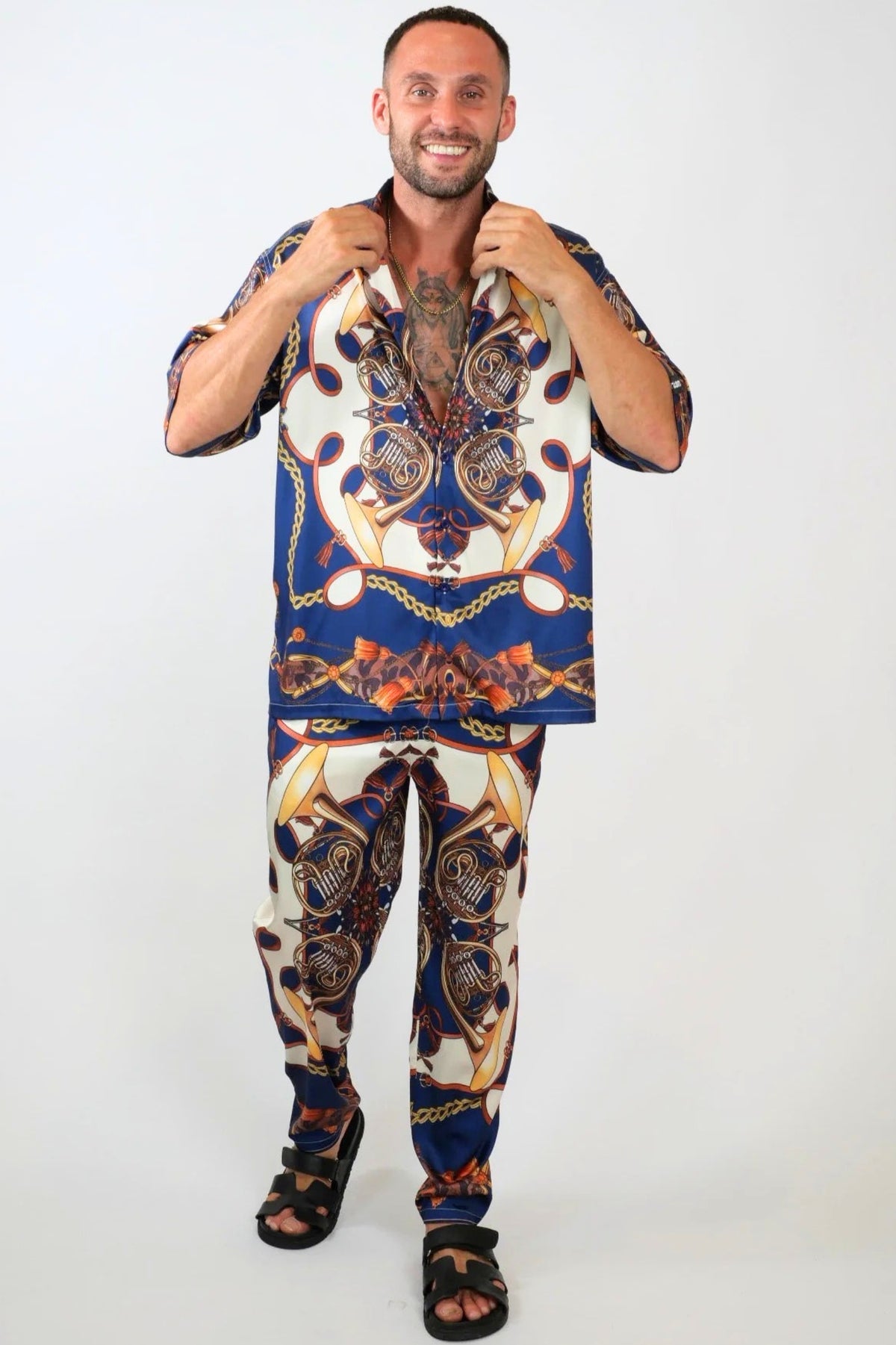 Man wearing a colorful patterned shirt and pants on a white background