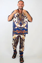 Man wearing a colorful patterned shirt and pants on a white background