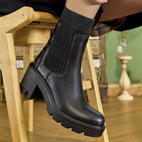 Black leather boot with a thick sole on a wooden chair