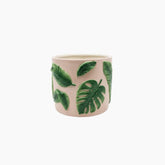 Ceramic mug with green leaf patterns on a white background