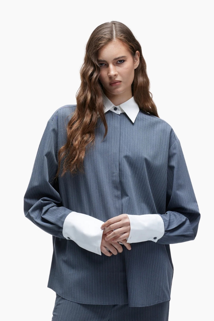 Woman wearing a blue pinstripe suit with a white shirt on a white background