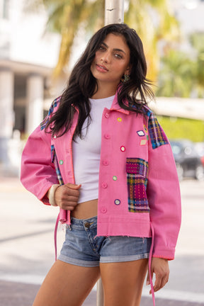 Woman wearing a colorful jacket with a plaid pattern, standing outdoors.