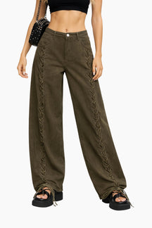 Person wearing olive green pants with lace-up sides on a white background