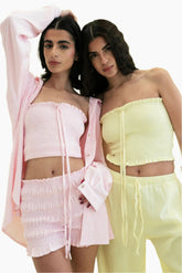 Two women wearing matching pink and yellow outfits.