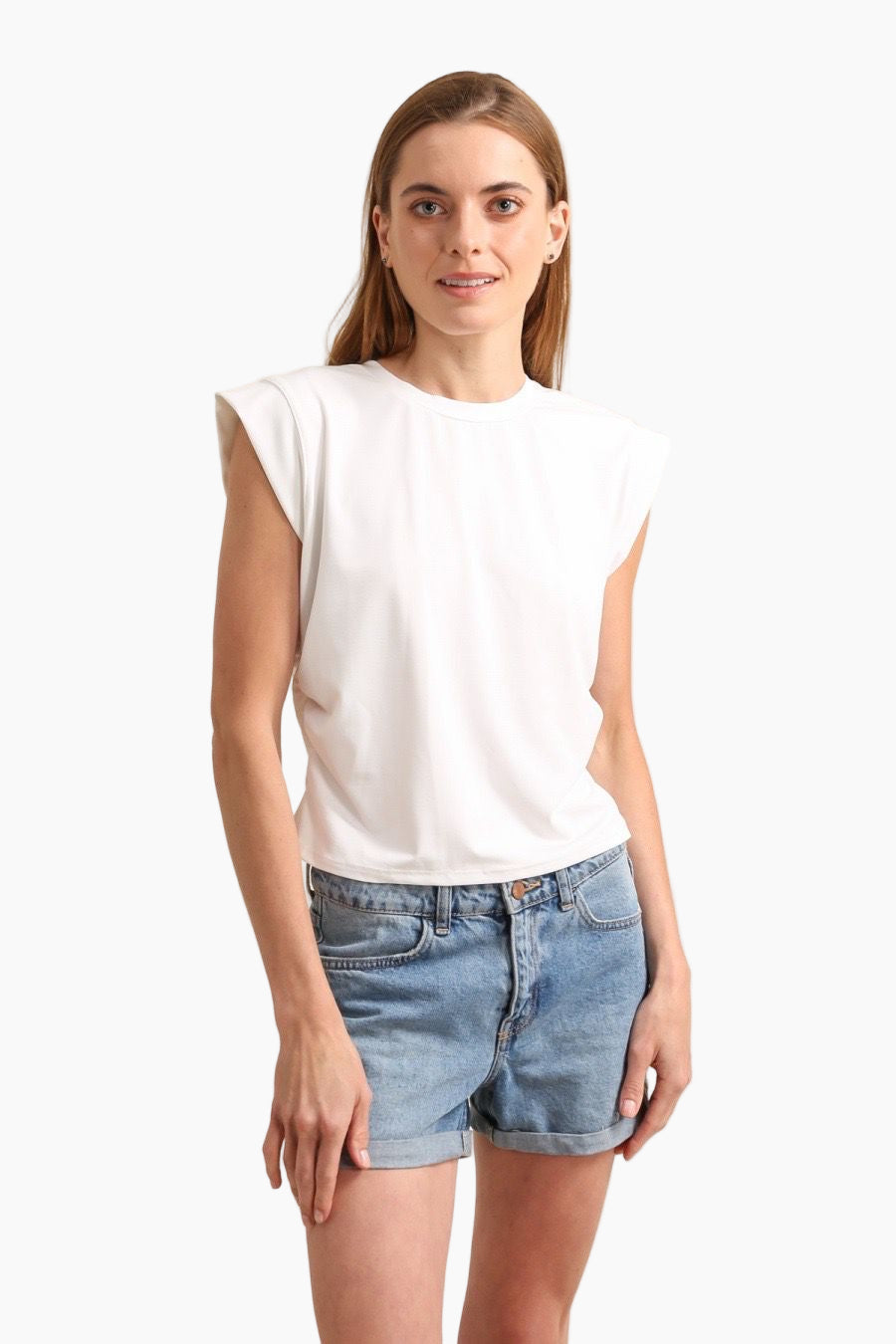 Woman wearing a white sleeveless top and denim shorts