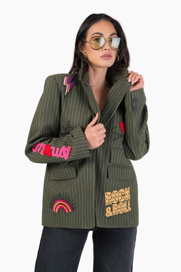 Woman wearing a green jacket with colorful patches and text 