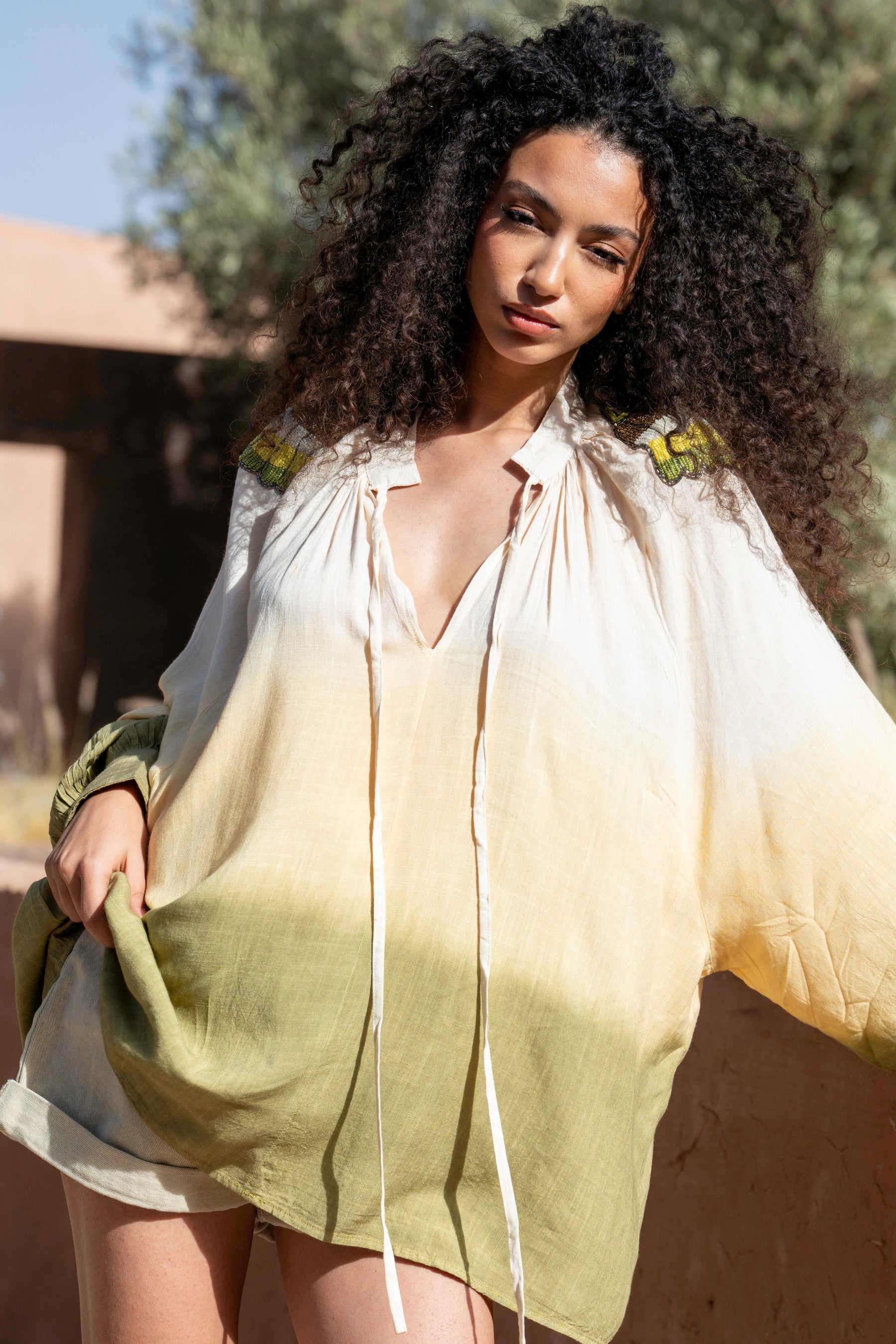 Woman wearing a light-colored dress with green accents outdoors