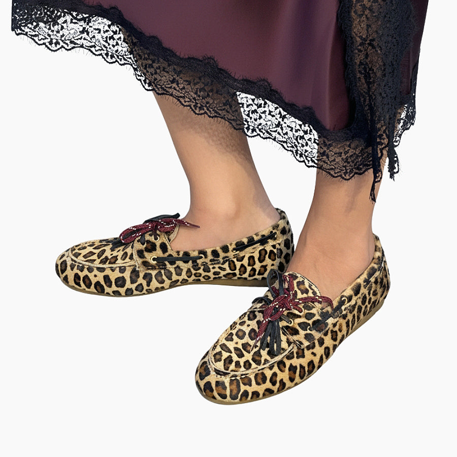 Leopard print shoes with red bows worn with a dark lace-trimmed skirt 