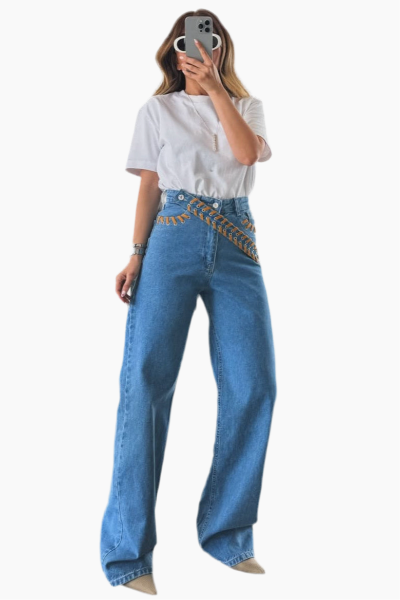 Person wearing blue jeans with a woven belt on a white background