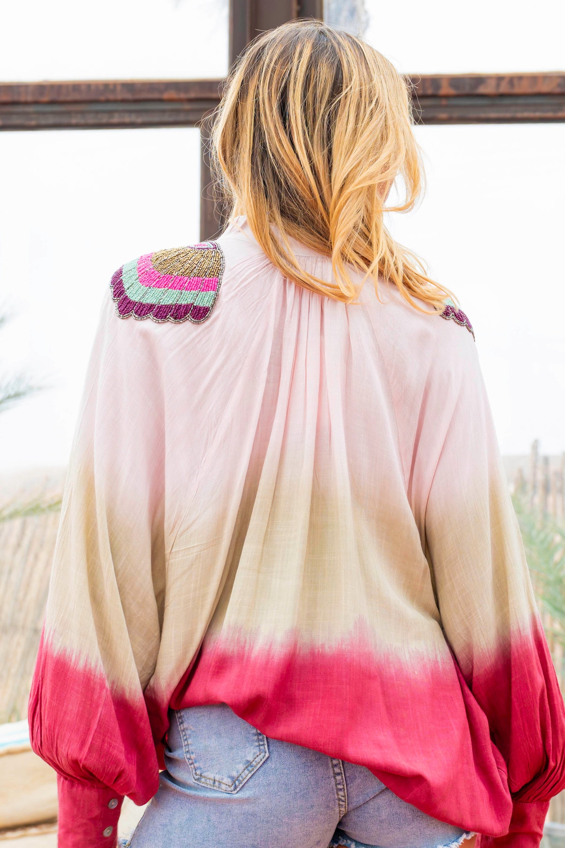 Woman wearing a colorful, gradient shirt with decorative shoulder pads.
