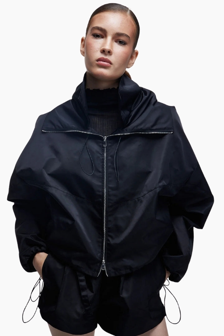 Person wearing a black jacket and shorts on a white background
