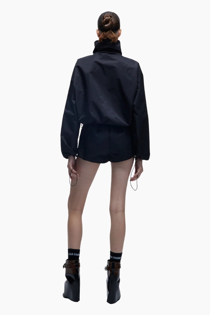 Person wearing a black outfit with a jacket and shorts on a white background