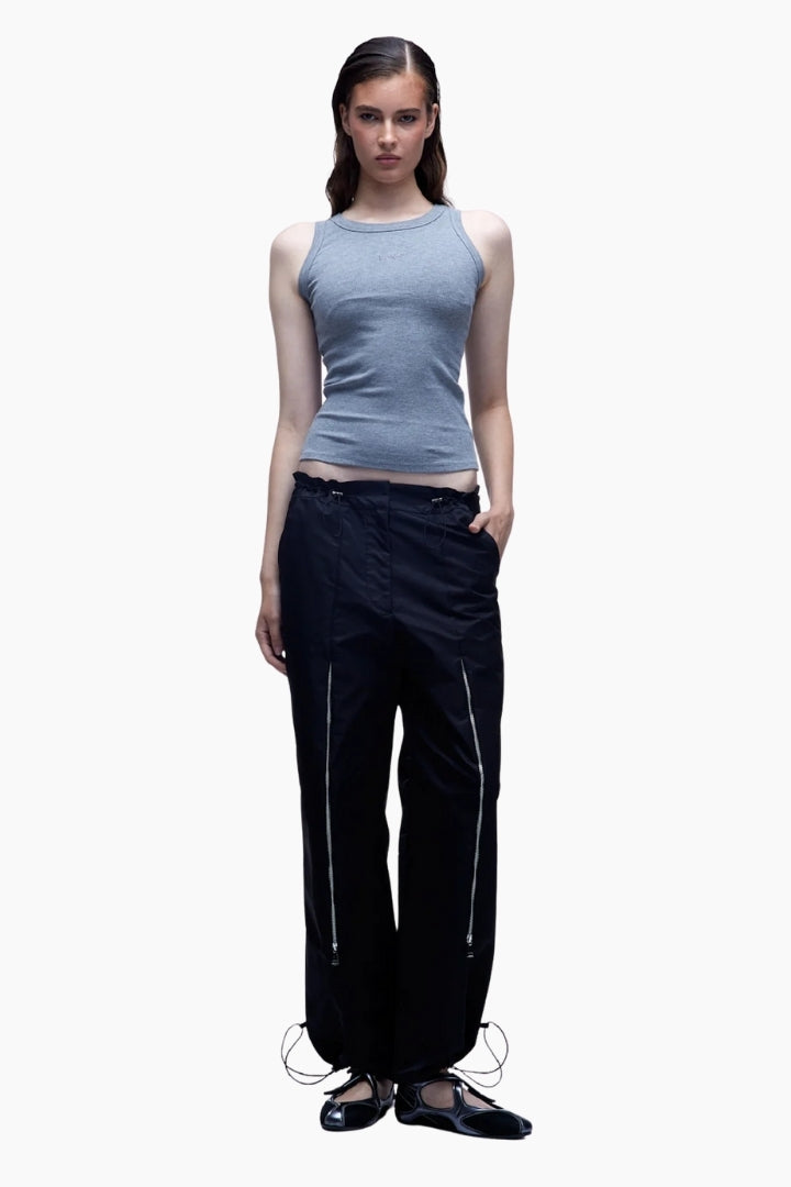 Woman wearing a light blue sleeveless top and black pants on a white background