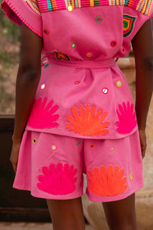Person wearing a bright pink outfit with shell patterns in an outdoor setting