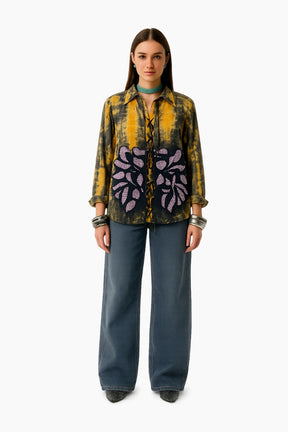 Woman wearing a patterned shirt and blue pants 