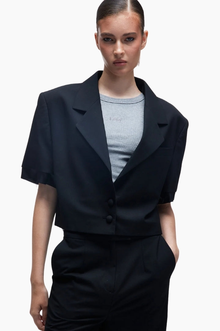 Woman wearing a black short-sleeve suit over a gray shirt 