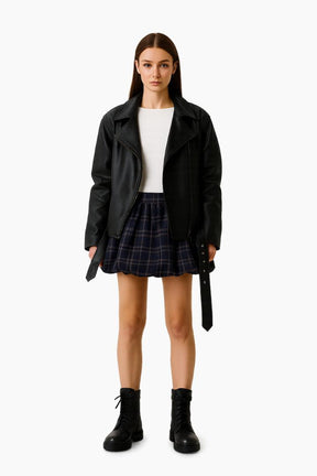 Person wearing a black leather jacket, white top, plaid skirt, and black boots 