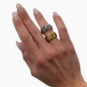 Hand wearing two rings on a plain background