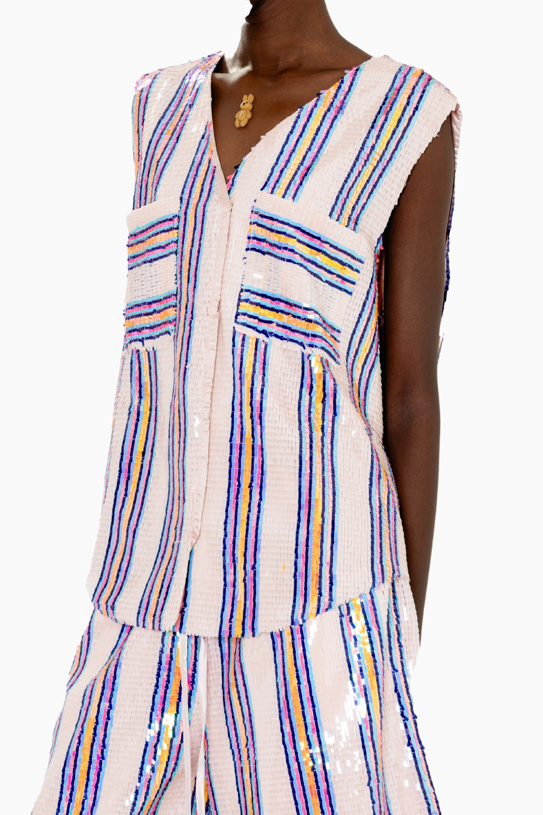 Woman wearing a Eye-catching vest featuring a sleeveless V-neck vest adorned with pastel and metallic vertical stripes for a shimmering finish.