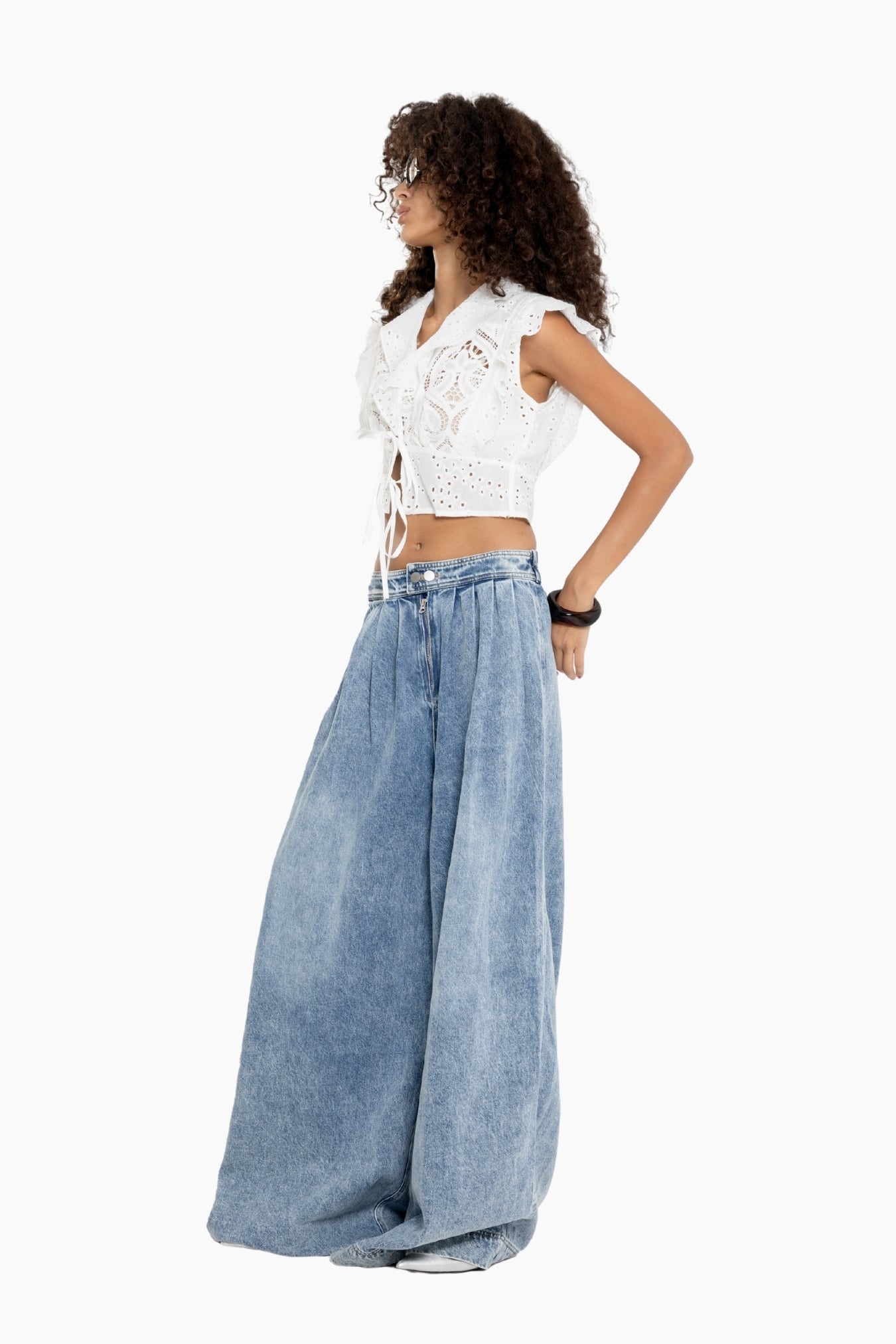 Woman wearing a white lace top and blue denim skirt 