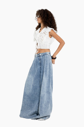 Woman wearing a white lace top and blue denim skirt 