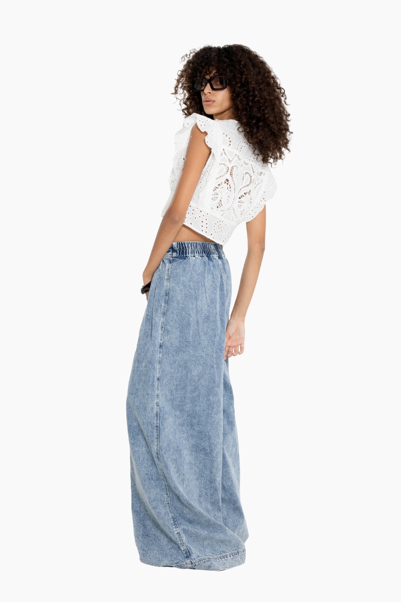 Woman wearing a white lace top and denim skirt 