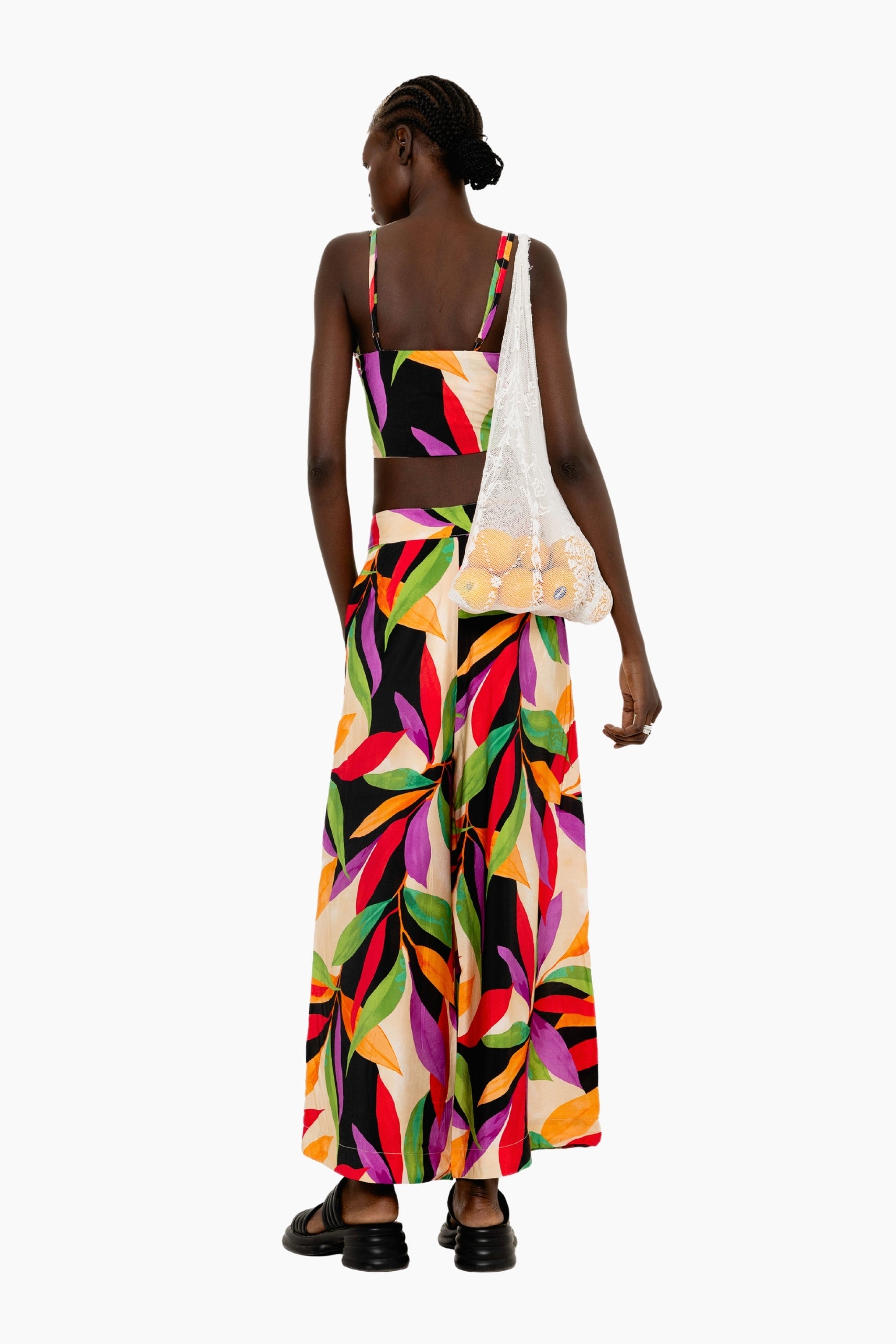 Model wearing a Flowing wide-leg pants with a striking oversized leaf motif in vivid hues.