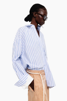 Person wearing a blue and white striped shirt with beige pants