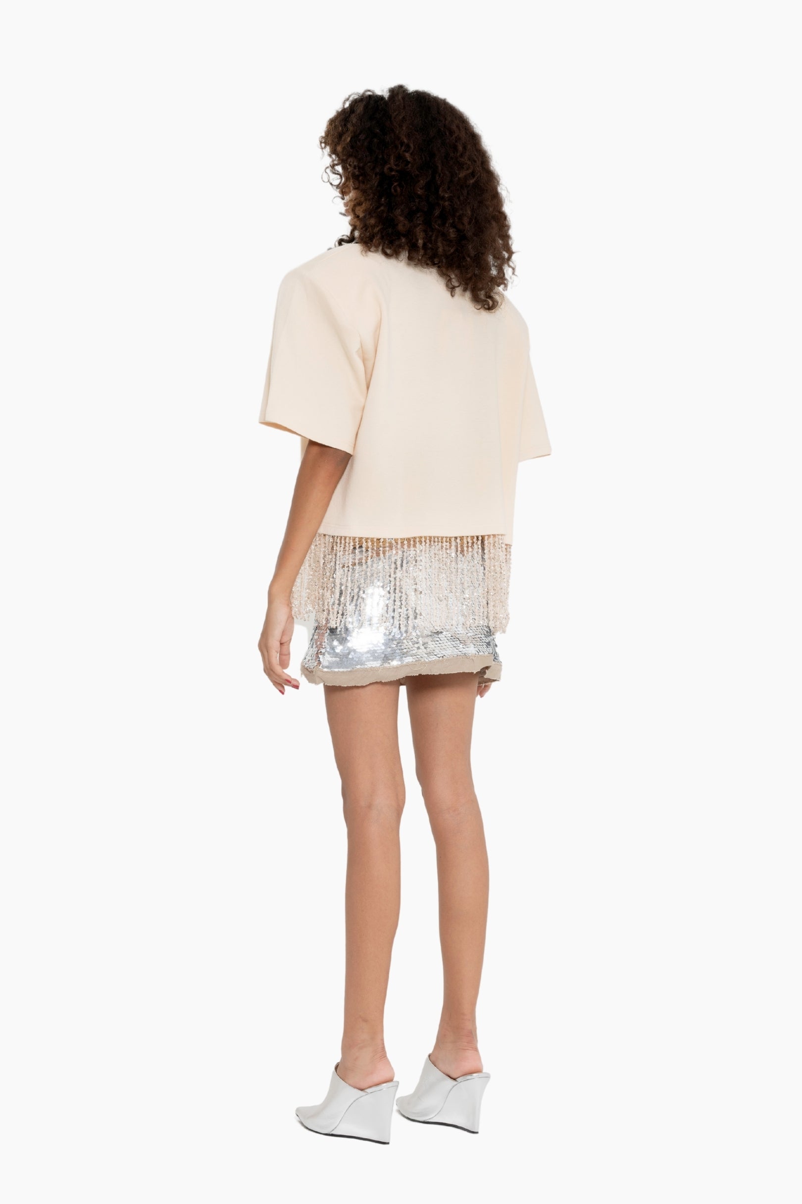 Person wearing a beige top and sequin skirt 