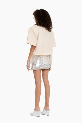 Person wearing a beige top and sequin skirt 