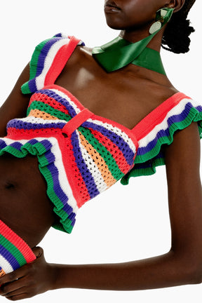 Person wearing a colorful crochet top with ruffled details on a white background