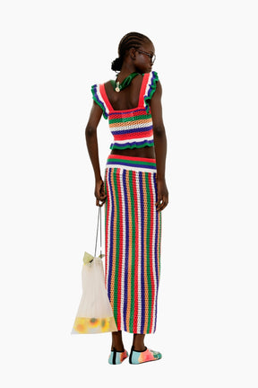 Woman wearing a colorful striped outfit holding a white bag 