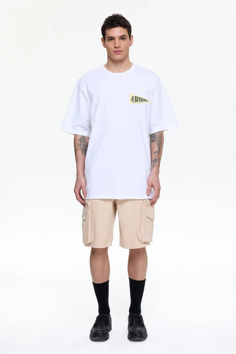 Person wearing a white t-shirt with a logo and beige cargo shorts 
