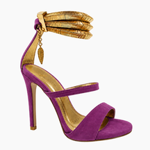 A purple suede high-heeled sandal with gold-tone metallic accents, including a wide top strap, stiletto heel, footbed lining, and an ankle cuff with a leaf charm, shown on a plain white background.
