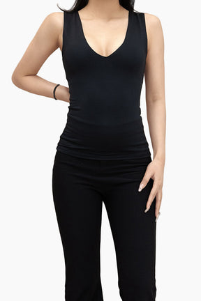 Person wearing a black sleeveless top and black pants on a white background