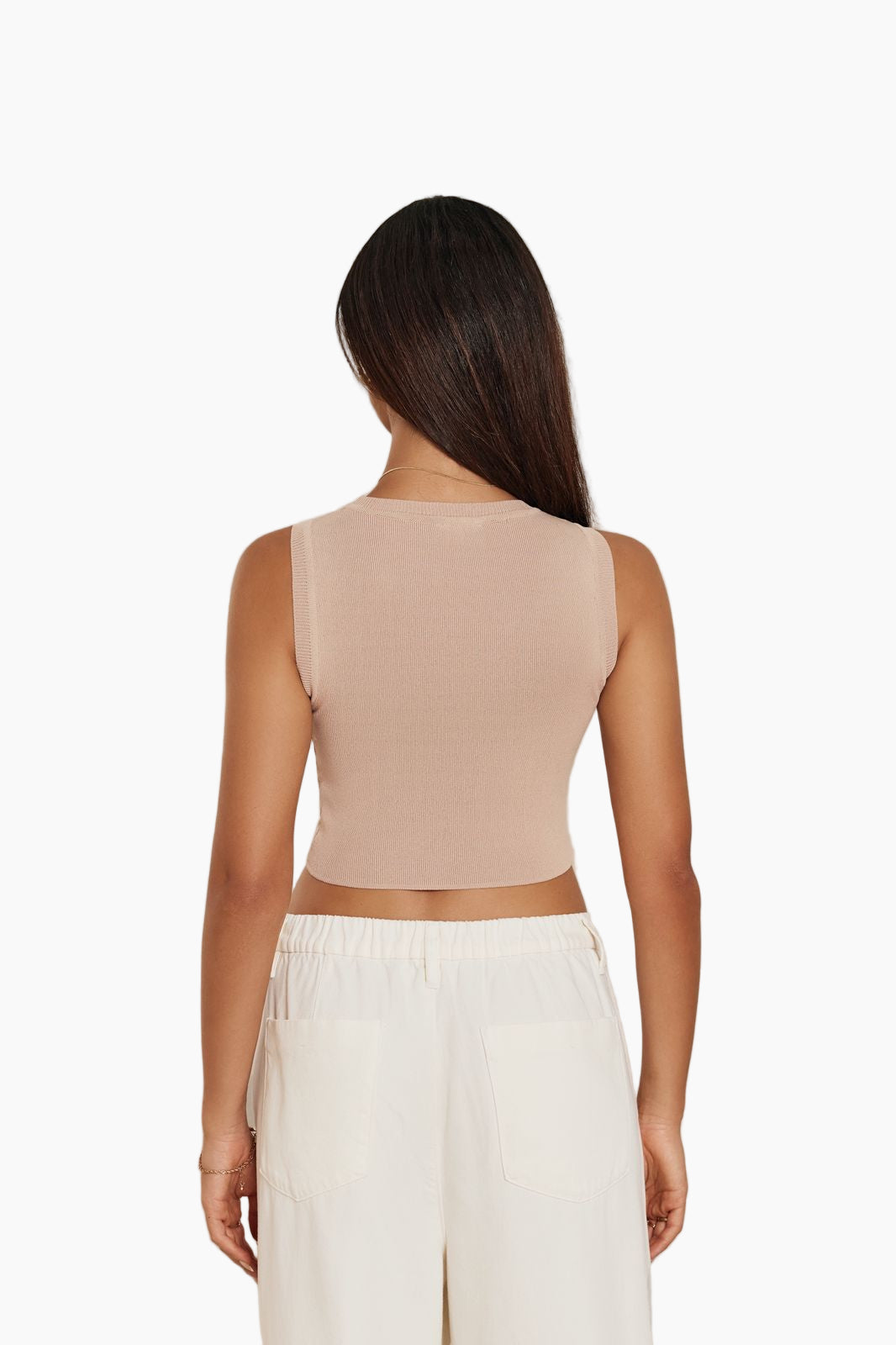 Woman wearing a beige sleeveless top and white pants