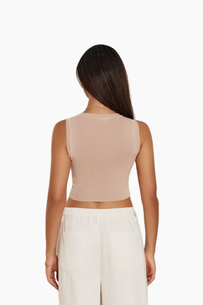 Woman wearing a beige sleeveless top and white pants