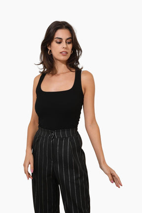 Woman wearing a black sleeveless top and black pinstripe pants 