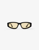 Black-framed sunglasses with yellow-tinted lenses on a white background