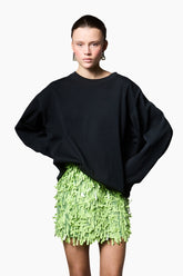 a green hue skirt Styled with oversized black tops