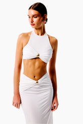 Woman wearing a white halter neck dress with gold accents 