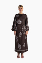 Woman wearing a brown dress with white patterns on a white background