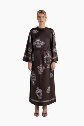 Woman wearing a brown dress with white patterns on a white background