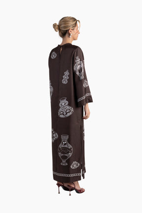Woman wearing a brown dress with white patterns on a white background